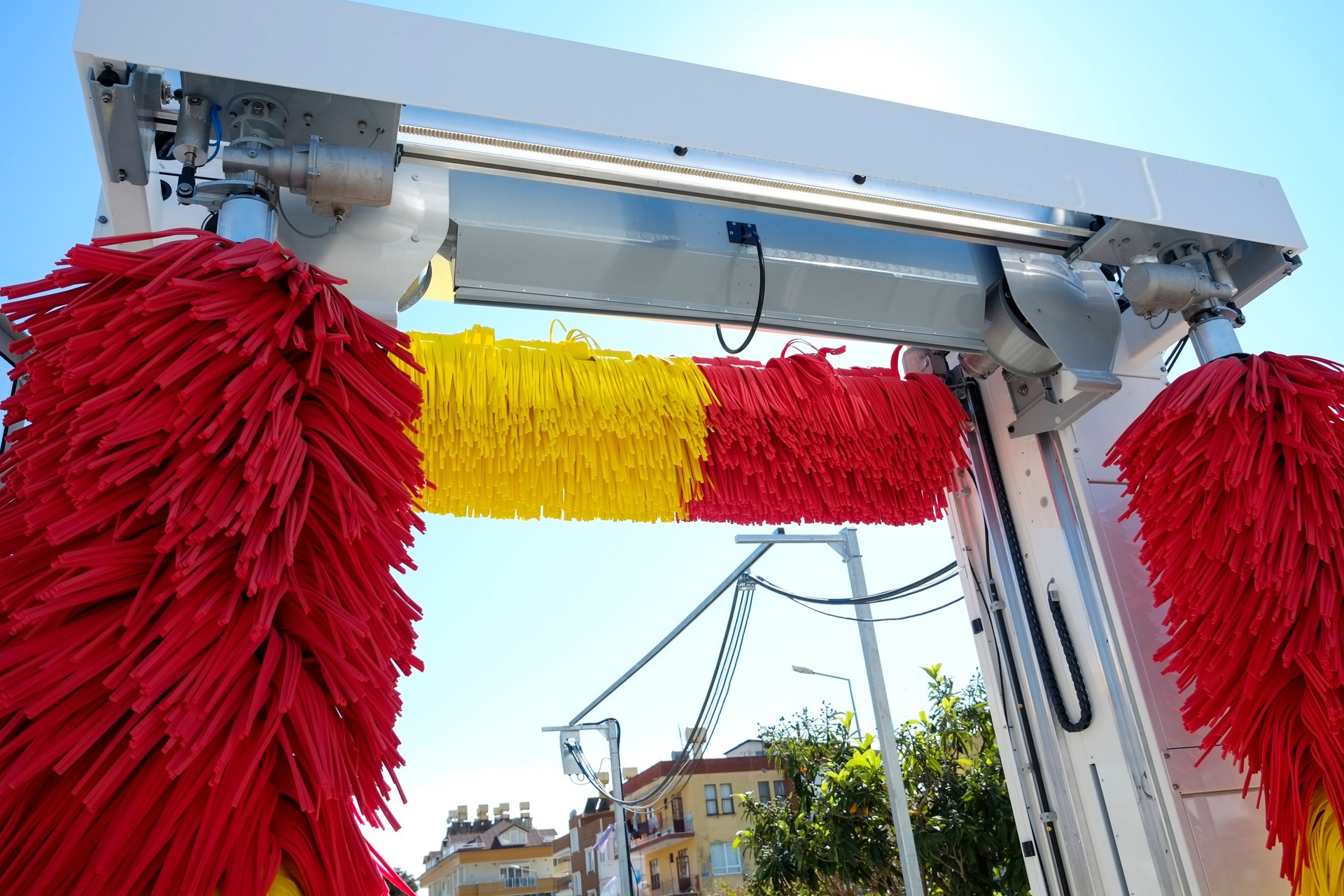 Empty outdoor self service car wash at gas station premises. Colorful red and yellow rotating carwash brushes. Close up, copy space, background.